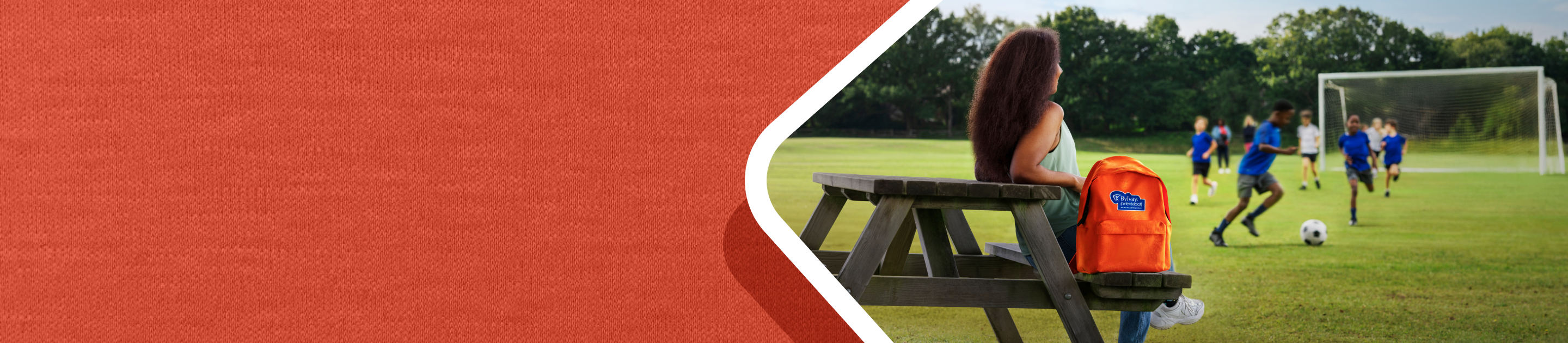 What is Alagille syndrome? Picture of a woman sitting at a picnic table next to the orange BYLVAY backpack.