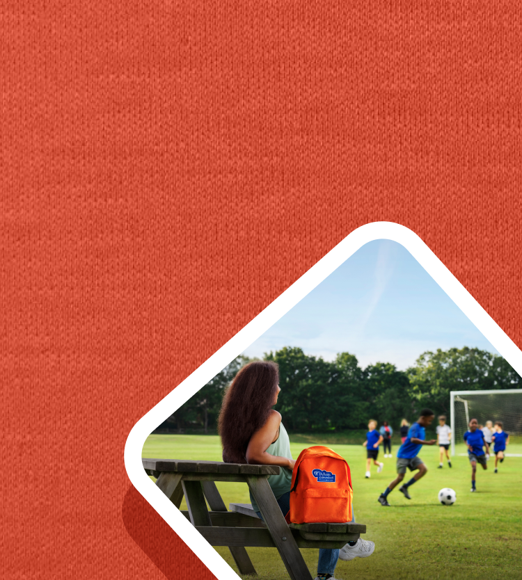 What is Alagille syndrome? Picture of a woman sitting at a picnic table next to the orange BYLVAY backpack.