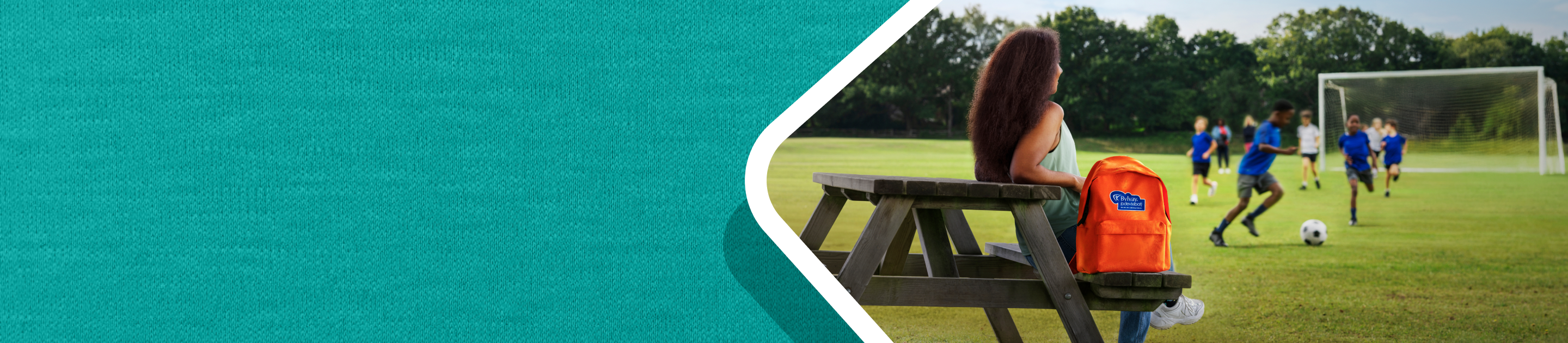 What is PFIC? Picture of a woman sitting at a picnic table next to the orange  BYLVAY backpack.